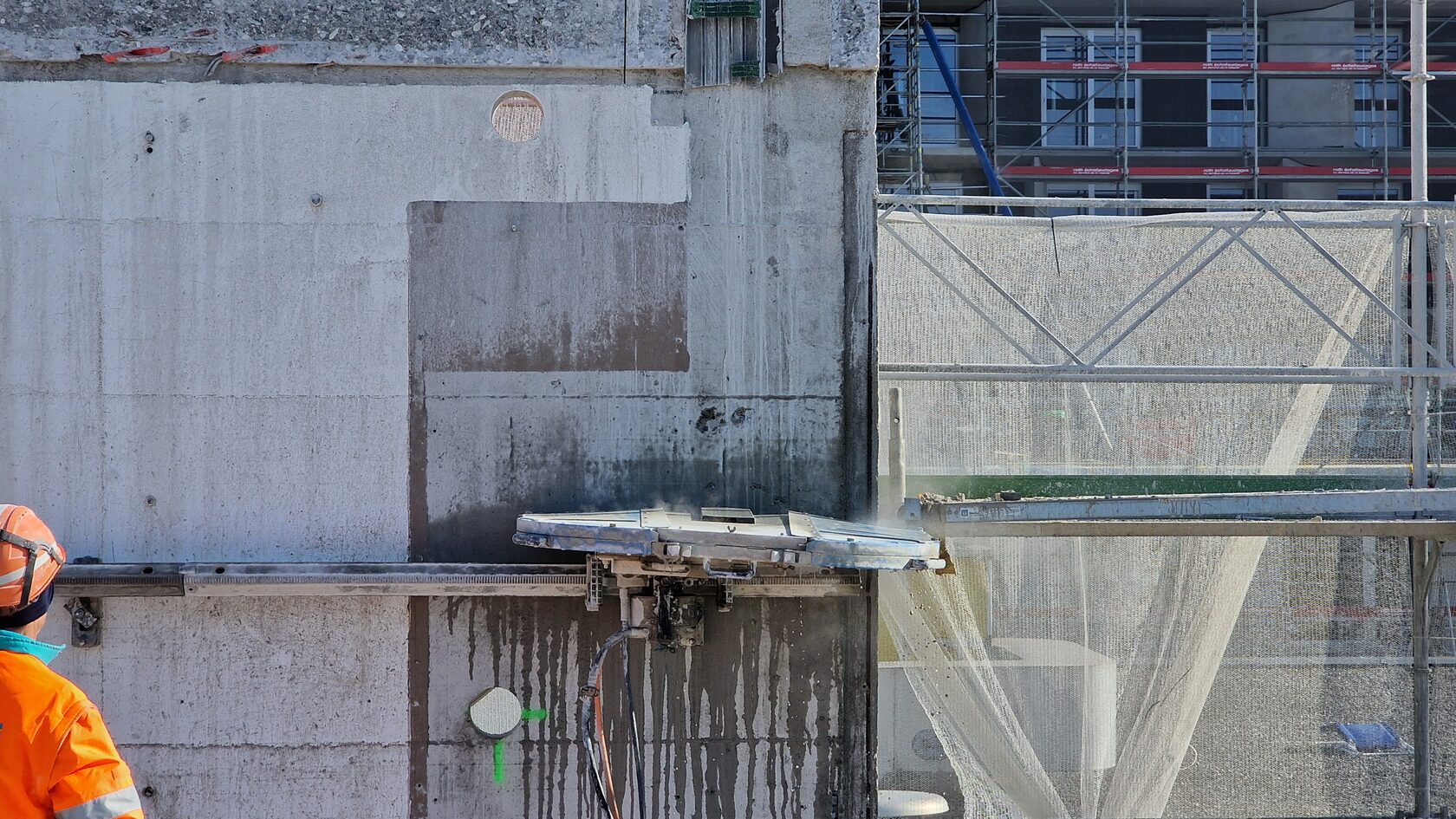 A rail-mounted diamond saw cutting a concrete wall.
